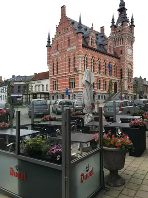 an outdoor cafe with tables and flowers in front of a building at Munal Hotel Temse in Temse