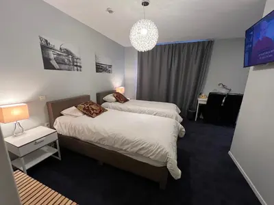 a hotel room with two beds and a television at Munal Hotel Temse in Temse