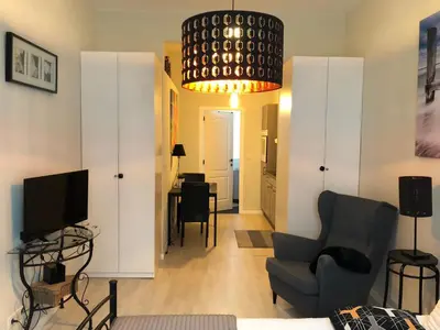 a living room with a couch and a chair and a television at Petit Appartement Jourdan EU in Brussels