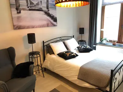a bedroom with a bed with two pillows and a chair at Petit Appartement Jourdan EU in Brussels