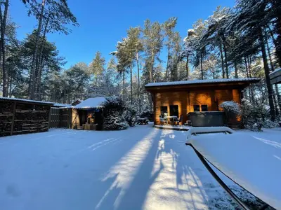 a log cabin in the snow with trees in the background at Casa Delux in Lille