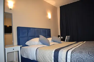 a bedroom with a bed with a blue headboard and a mirror at Hôtel Méribel in Brussels