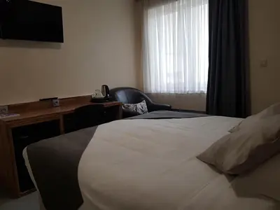 a hotel room with a bed and a desk and a television at Hôtel Méribel in Brussels