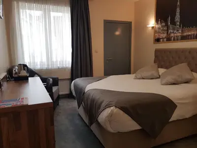 a hotel room with two beds and a desk at Hôtel Méribel in Brussels