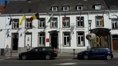 two cars parked in front of a building with flags at B&B prince d’Orange Waterloo in Waterloo