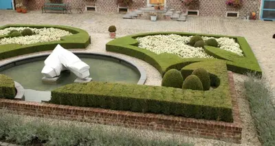 a garden with hedges and a pool of water at Onsemhoeve in Dilbeek