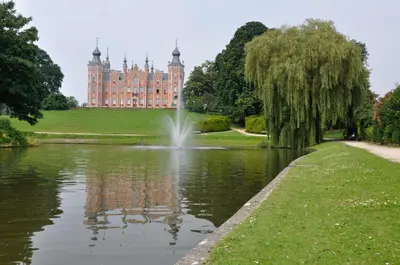 a castle with a pond in front of a building at Onsemhoeve in Dilbeek