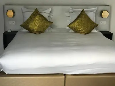 a large white bed with gold pillows on it at Koto Garden Suites in Antwerp