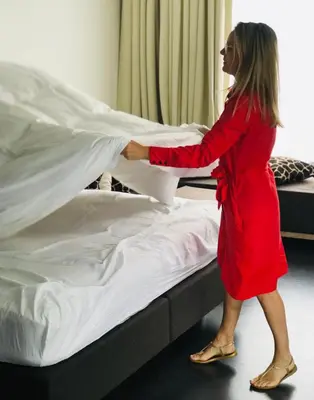 a woman in a red dress putting sheets on a bed at Koto Garden Suites in Antwerp