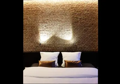 a bedroom with a brick wall and a bed with pillows at Hotel Goodnight Antwerp in Antwerp