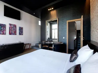 a bedroom with a large white bed and a desk at Hotel Goodnight Antwerp in Antwerp