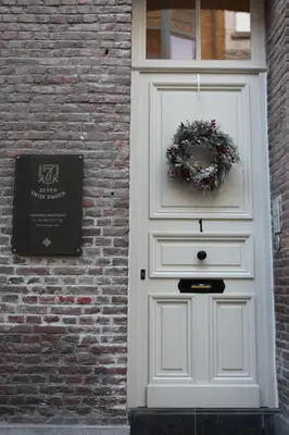 a white door with a wreath on a brick wall at ZevenVrijeDagen in Ghent