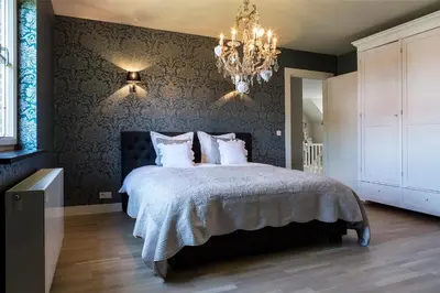 a bedroom with a large bed with a chandelier at B&B Vinedo in Zele