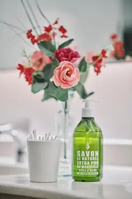 a bottle of soap next to a vase with flowers at The Legacy by 2GO4 City Center in Brussels