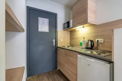 a kitchen with a door leading into a kitchen with wooden cabinets at Value Stay Residence Mechelen in Mechelen