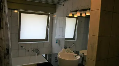 a bathroom with two sinks and a tub and two windows at De Basiliek in Edegem