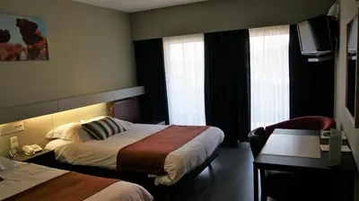 a hotel room with two beds and a desk at De Basiliek in Edegem