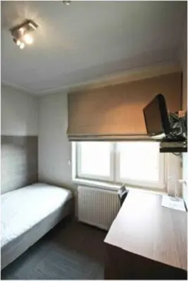 a small bedroom with a bed and a window at Hotel de modern in Diest