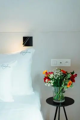a vase of flowers sitting on a table next to a bed at The House of Edward by Domani Hotels in Ghent