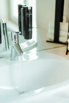 a bathroom counter with a bottle of perfume on it at The House of Edward by Domani Hotels in Ghent