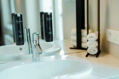 a bathroom sink with a faucet in front of a mirror at The House of Edward by Domani Hotels in Ghent