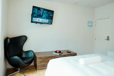 a bedroom with a chair and a tv on the wall at The House of Edward by Domani Hotels in Ghent