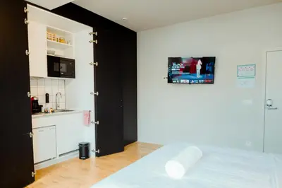 a bedroom with a white bed and a kitchen at The House of Edward by Domani Hotels in Ghent