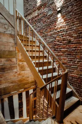 a wooden staircase in front of a brick wall at The House of Edward by Domani Hotels in Ghent