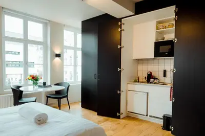 a bedroom with a bed and a table and a kitchen at The House of Edward by Domani Hotels in Ghent