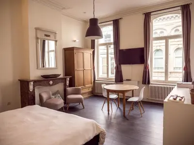 a bedroom with a bed and a table and chairs at Maison Willem Tell in Ghent