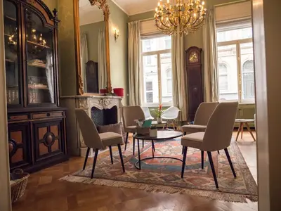 a living room with chairs and a table and a chandelier at Maison Willem Tell in Ghent