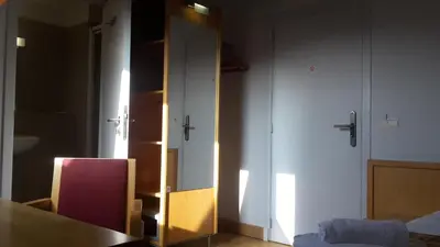 a room with a table and a cabinet with a mirror at Irish College Leuven in Leuven