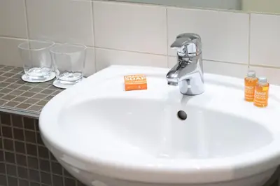 a bathroom sink with two glasses and a faucet at Hotel Chambord in Brussels