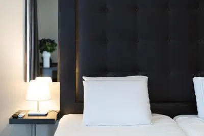 a bed with a black headboard and a white pillow at Hotel Chambord in Brussels