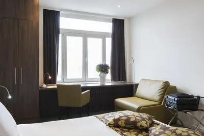 a bedroom with a bed and a chair and a window at Hotel Chambord in Brussels