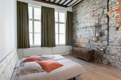 a bedroom with a large bed in a brick wall at Hof Van Spanje in Ghent