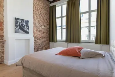 a bedroom with a bed with a brick wall and windows at Hof Van Spanje in Ghent