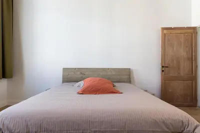 a bed with an orange pillow on top of it at Hof Van Spanje in Ghent