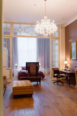 a living room with a chandelier and a table and chairs at Park Hotel Brussels in Brussels
