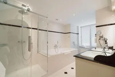 a bathroom with a shower and a sink and a tub at Park Hotel Brussels in Brussels