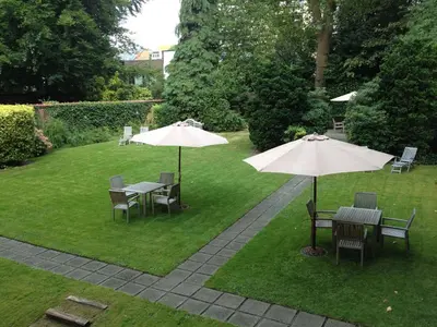 two tables and chairs with umbrellas on a lawn at Park Hotel Brussels in Brussels