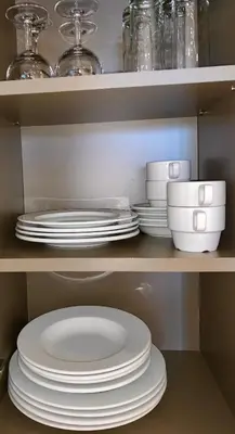 a stack of plates and bowls on a shelf at Castelnou Aparthotel in Ghent