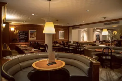 a restaurant with a couch and tables and chairs at Castelnou Aparthotel in Ghent