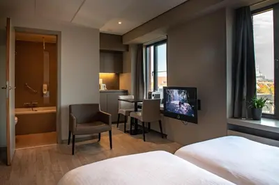a hotel room with a television and a bathroom at Castelnou Aparthotel in Ghent