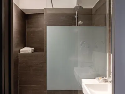 a bathroom with a glass shower and a sink at Hotel Gravensteen in Ghent