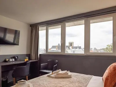 a hotel room with a bed and two chairs and windows at Hotel Gravensteen in Ghent