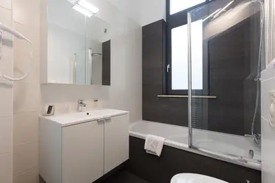 a white bathroom with a sink and a shower at Hotel Gravensteen in Ghent