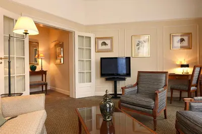 a living room with a couch and a tv at Hotel Le Plaza Brussels in Brussels
