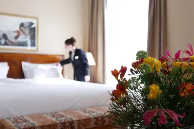 a man in a suit standing next to a bed at Hotel Le Plaza Brussels in Brussels