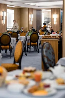 a dining room with tables and people sitting at tables at Hotel Le Plaza Brussels in Brussels